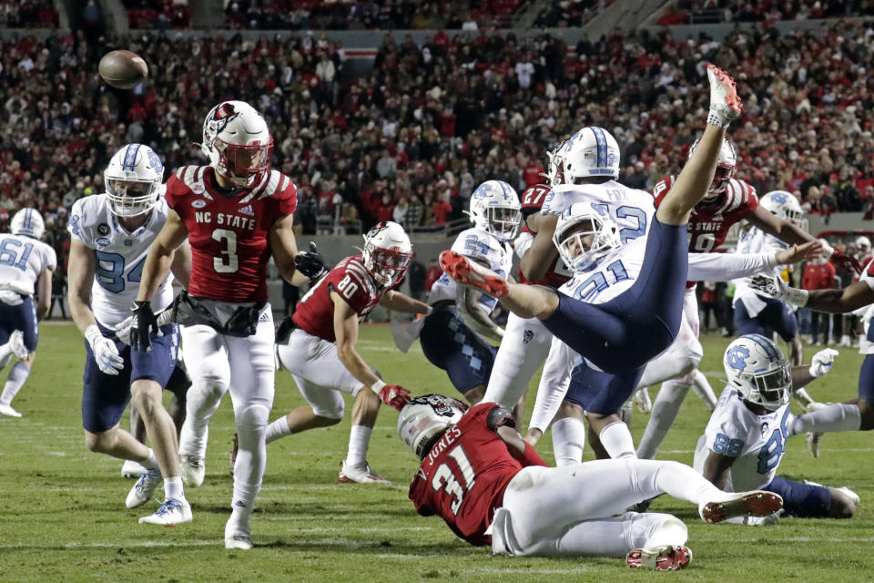 North Carolina punter Ben Kiernan (91) is upended after North Carolina State linebacker Vi Jones (31) blocked his punt during the first half of an NCAA college football game Friday, Nov. 26, 2021, in Raleigh, N.C. (AP Photo/Chris Seward)