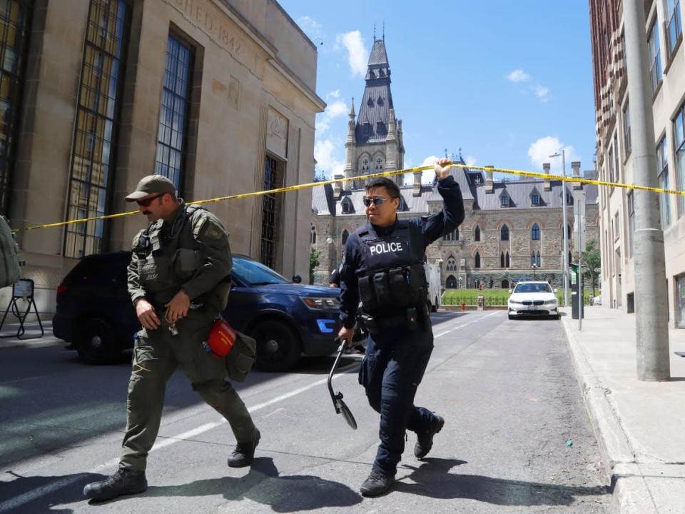 First responders lift tape blocking off streets around Parliament Hill as they responded to reports of a possible threat, which turned out to be unfounded. (Patrick Doyle/The Canadian Press - image credit)