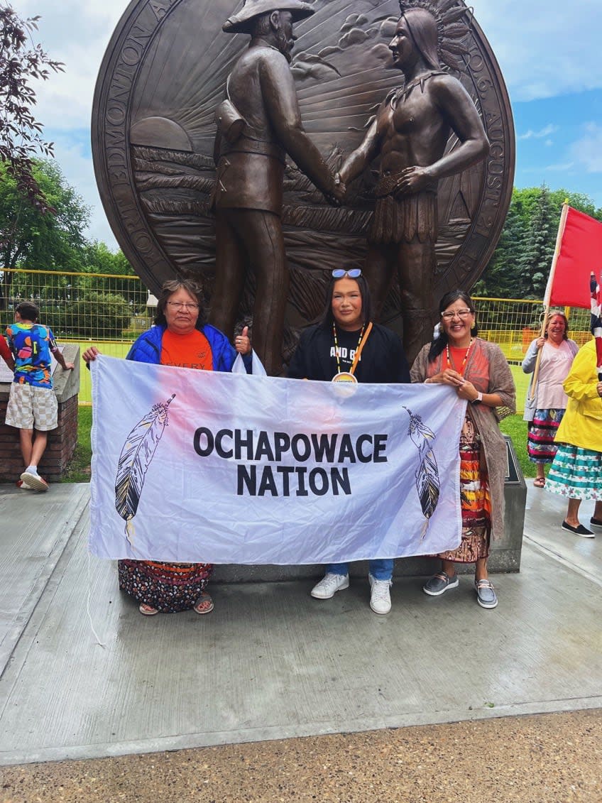 Tyler George, centre, holding up a flag of his home community, Ochapowace Nation. 