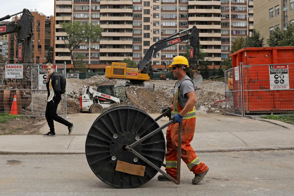 A construction worker passes a condominium site with a roll of cable in Toronto, Ontario, Canada October 8, 2021.  REUTERS/Chris Helgren