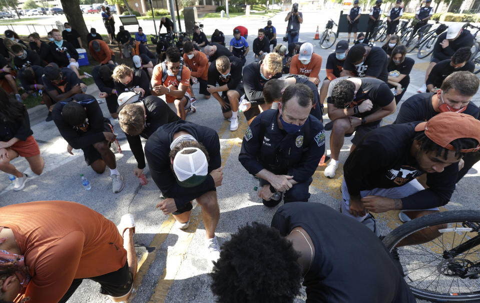 Members of the Austin Police Department kneel with members of the University of Texas football team in Austin, Texas, Thursday, June 4, 2020, after they marched to the State Capitol, during a protest over the death of George Floyd, who died May 25 after being restrained by police in Minneapolis. (AP Photo/Eric Gay)