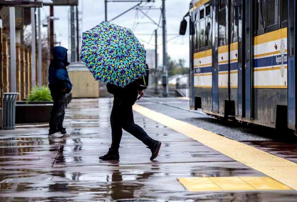 A light rail passenger departs the train with an umbrella at Sacramento City College on Tuesday, March 28, 2023.