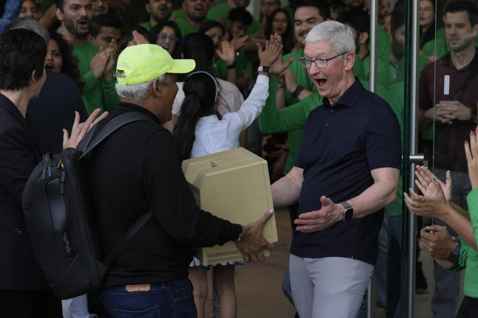 Apple CEO Tim Cook, right, reacts after seeing an old Macintosh Classic machine brought by a visitor during the opening of the first Apple Inc. flagship store in Mumbai, India, Tuesday, April 18, 2023. Apple Inc. opened its first flagship store in India in a much-anticipated launch Tuesday that highlights the company's growing aspirations to expand in the country it also hopes to turn into a potential manufacturing hub. (AP Photo/Rafiq Maqbool)