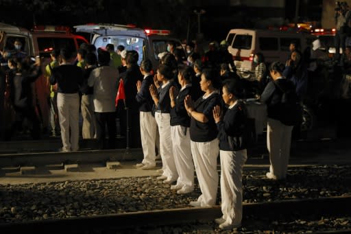 Members of a Buddhist group offer prayers along the rail tracks after the Puyuma Express train derailed at high speed