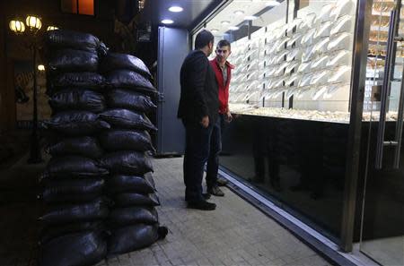 Men chat as piled sandbags are erected in front of a jewellery shop as protection from future explosions at a stronghold of the Shi'ite group Hezbollah in the southern suburbs of the Lebanese capital Beirut January 28, 2014. REUTERS/Hasan Shaaban