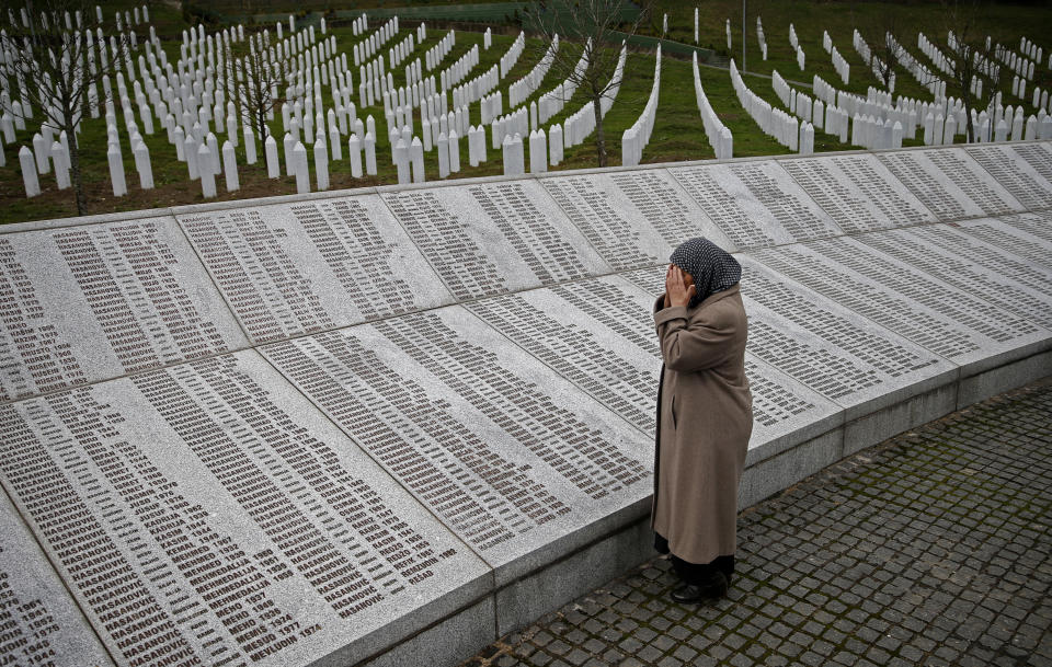 A woman prays near a memorial plaque with the names of those killed in the Srebrenica massacre.