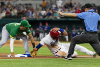 Texas Rangers' Joey Gallo, center, avoids the tag of Oakland Athletics third baseman Chad Pinder, left, to safely take third base during the first inning of a baseball game, Monday, June 21, 2021, in Arlington, Texas. (AP Photo/Sam Hodde)