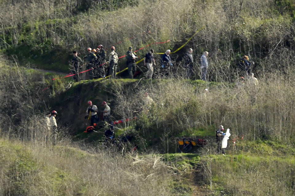 FILE - In this Jan. 27, 2020, file photo, investigators work the scene of a helicopter crash that killed former NBA basketball player Kobe Bryant, his 13-year-old daughter, Gianna, and several others in Calabasas, Calif. Federal investigators said Wednesday, June 17, 2020, that the pilot of the helicopter that crashed in thick fog, killing Kobe Bryant and seven other passengers, reported he was climbing when he actually was descending. (AP Photo/Mark J. Terrill, File)