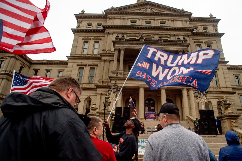 A protester waves a Trump flag during rally at the Michigan Capitol, Oct. 12, 2021, in Lansing.