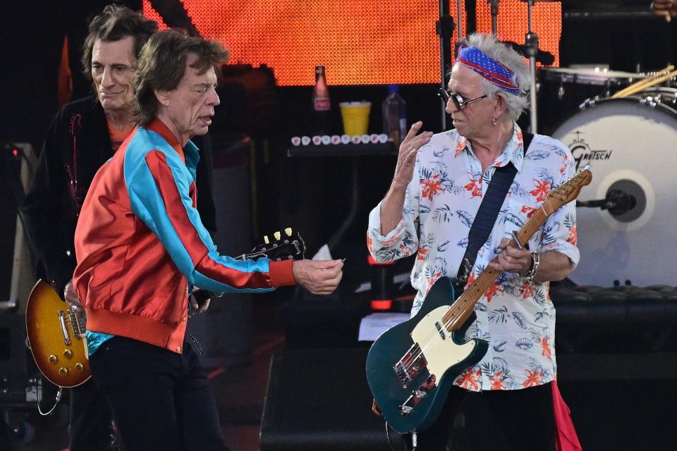 British rock band The Rolling Stones' singer Mick Jagger (front) hands guitarist Keith Richards (2nd R) his plectrum he dropped while performing on stage with guitarist Ron Wood (L) and drummer Steve Jordan during a concert as part of their 'Stones Sixty European Tour' at the Waldbuehne at Olympiapark in Berlin on August 3, 2022. - RESTRICTED TO EDITORIAL USE. ALTERNATIVE CROP (Photo by INA FASSBENDER / AFP) / RESTRICTED TO EDITORIAL USE. ALTERNATIVE CROP (Photo by INA FASSBENDER/AFP via Getty Images)