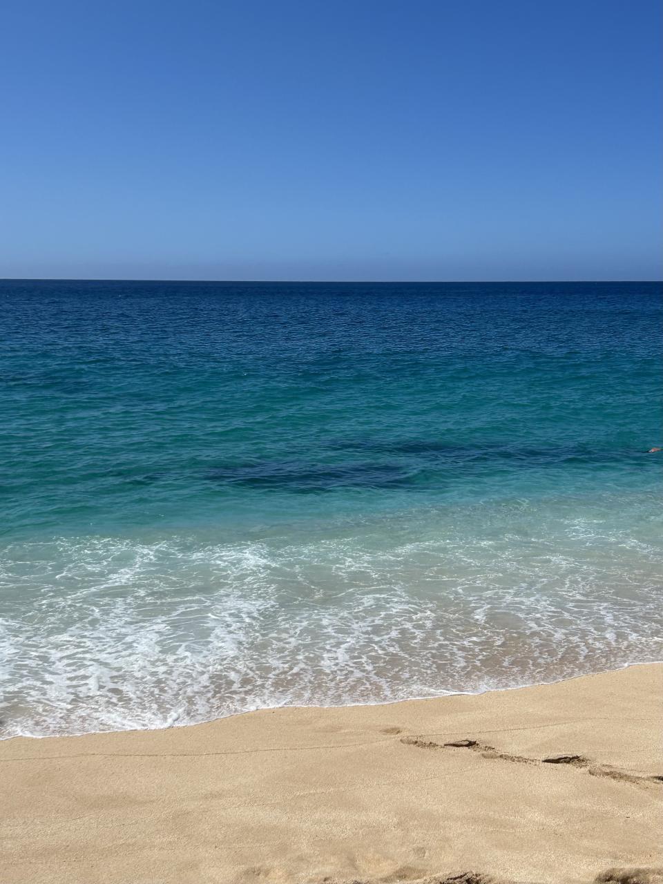 Beach with clear blue water meeting a sandy shore, no people in view