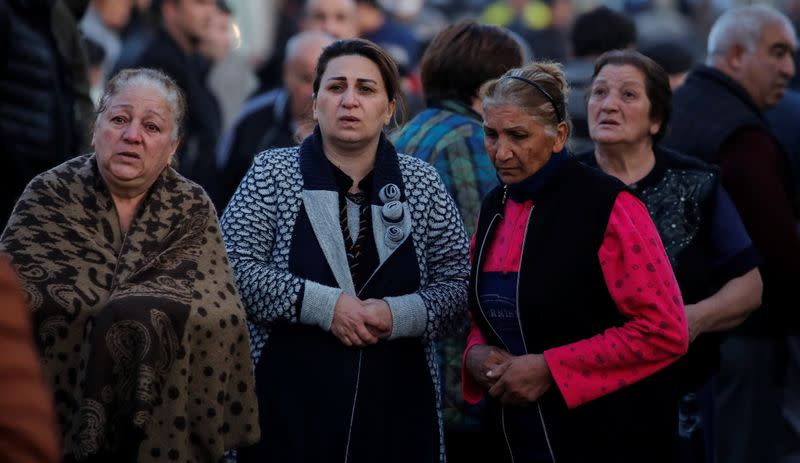 Residents wait at a blast site hit by a rocket in the city of Ganja