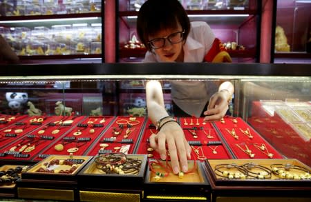 FILE PHOTO: A sales assistant takes out gold ornaments for a customer at Caibai Jewelry store in Beijing