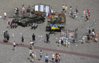 People visit an open-air exhibition of damaged and burnt-out Russian tanks and armored vehicles at the Castle Square, in Warsaw, Poland, Monday, June 27, 2022. The vehicles were captured by Ukrainian military forces during the war in the Ukraine. Ukrainian authorities announced that there are plans for similar exhibits in other European capitals such as Berlin, Paris, Madrid and Lisbon. (AP Photo/Michal Dyjuk)