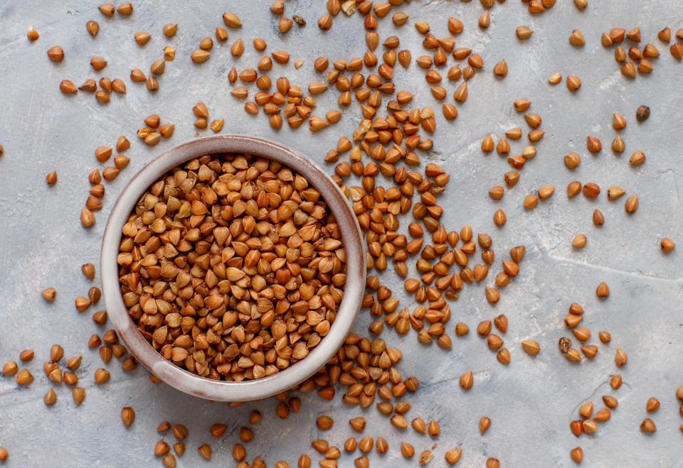 Raw dry buckwheat grain in and around a bowl