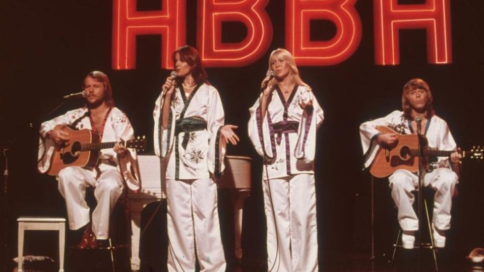 El grupo ABBA al completo en un escenario cantando.