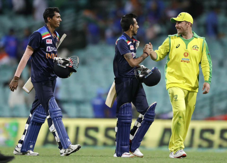 Australia's Aaron Finch, right, shakes hands with India's Yuzendra Chahal, centre, as Navdeep Saini, left, watches following the one day international cricket match between India and Australia at the Sydney Cricket Ground in Sydney, Australia, Sunday, Nov. 29, 2020. (AP Photo/Rick Rycroft)