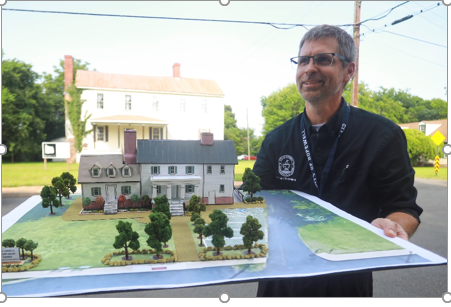Charles Bennett, Director of Economic Development and Tourism, holds a model of the completed project to compare with the existing conditions of Shiloh Lodge #33 in the background.