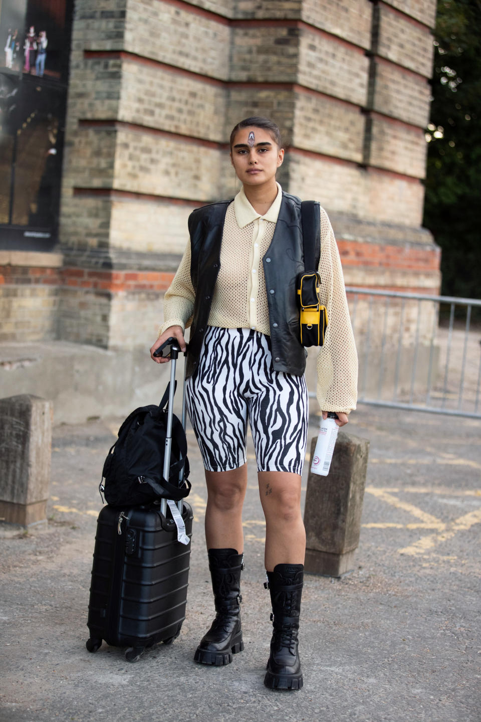 LONDON, ENGLAND - SEPTEMBER 15: Model Jill Kortleve wears a black leather vest, cream top, white zebra print track shorts, black Prada boots, a black backpack, a black rolling suitcase, and the feather handpainted makeup by Thomas de Kluyver after the Simone Rocha show during London Fashion Week September 2019 on September 15, 2019 in London, England. (Photo by Melodie Jeng/Getty Images)