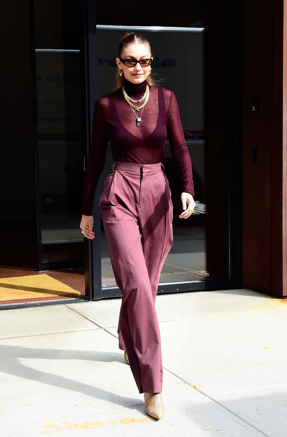 <p>In a sheer wine turtleneck, bra, high-waisted trousers, black shades, <a href="https://www.liliclaspe.com/collections/just-listed/products/mia-hoops-small" rel="nofollow noopener" target="_blank" data-ylk="slk:gold crescent hoops" class="link ">gold crescent hoops</a> by Lili Claspe, the <a href="https://www.missoma.com/shop/categories/necklaces/chain-necklaces/9323/lucy-williams-gold-chunky-chain-necklace/" rel="nofollow noopener" target="_blank" data-ylk="slk:T Bar Chunky Chain Necklace" class="link ">T Bar Chunky Chain Necklace</a> by Missoma, and pointed python boots.</p>
