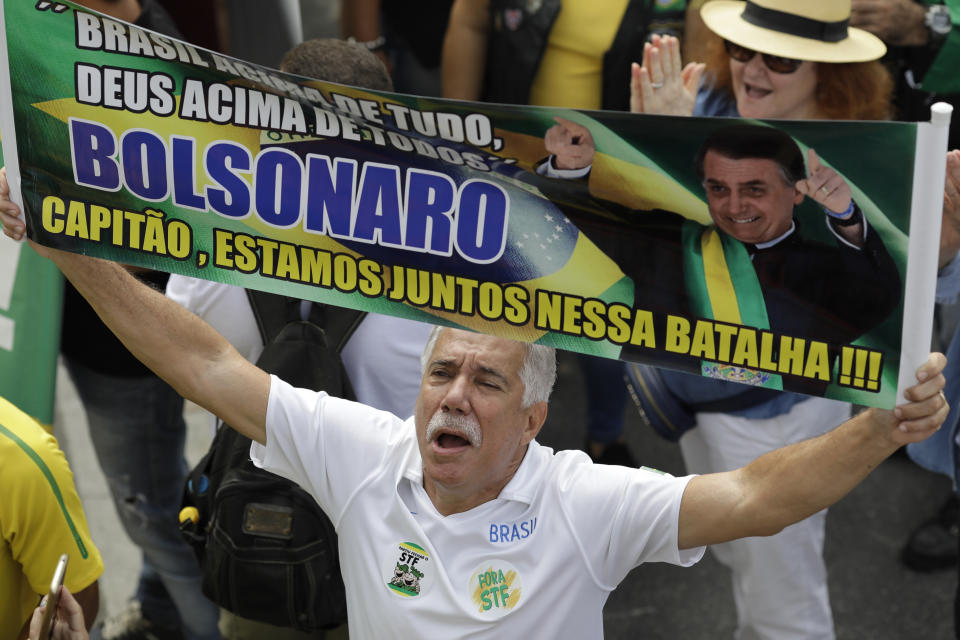 A supporter of Brazil's President Jair Bolsonaro holds the Portuguese message: "Bolsonaro, captain, we are in this battle together" on Copacabana beach in Rio de Janeiro, Brazil, Sunday, May 26, 2019. The pro-Bolsonaro rally follows anti-government protests against cuts in the education budget as the president also battles an uncooperative Congress, a family corruption scandal and falling approval ratings after five months in office. (AP Photo/Silvia Izquierdo)