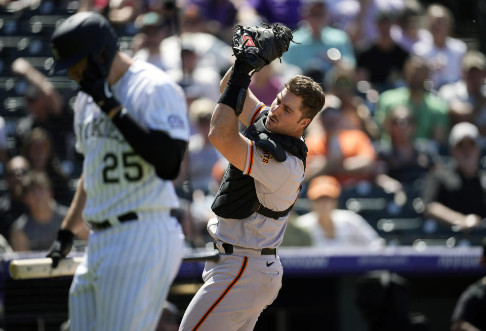 San Francisco Giants catcher Joey Bart, right, fields a pop foul off the bat of Colorado Rockies' C.J. Cron in the sixth inning of a baseball game Wednesday, May 18, 2022, in Denver. (AP Photo/David Zalubowski)