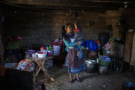 Alba Organiz holds her son Rudy Anibal while preparing food for guests who have come to pay their respects to the family of Santa Perez, in Comitancillo, Guatemala, Wednesday, Jan. 27, 2021. They believe that Santa Perez is one the charred corpses found in a northern Mexico border state on Saturday. The country's Foreign Ministry said it was collecting DNA samples from a dozen relatives to see if there was a match with any of the bodies. (AP Photo/Oliver de Ros)