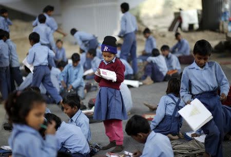 A schoolgirl reads from a textbook at an open-air school in New Delhi November 20, 2014. REUTERS/Anindito Mukherjee