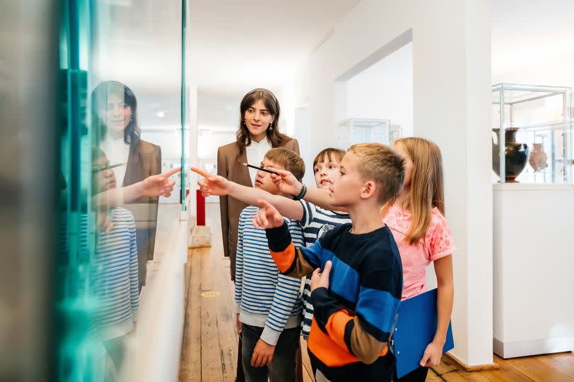 A group of young children looking at objects and images on display while on a school trip to a museum.