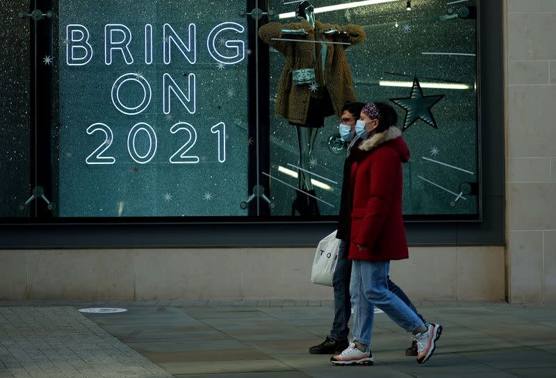 FILE PHOTO: People walk past a sign in a shop window amid the outbreak of the coronavirus disease (COVID-19) in Manchester, Britain