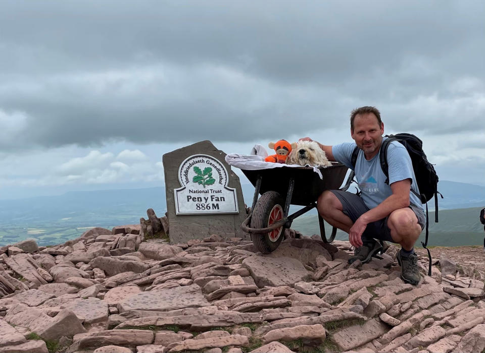 Carlos Fresco took his dying pet dog Monty up Pen y Fan in the Brecon Beacons on one last walk, pushing him in a wheelbarrow. (SWNS)
