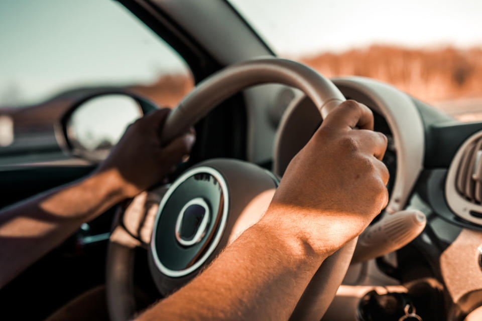 A person holding a car steering wheel