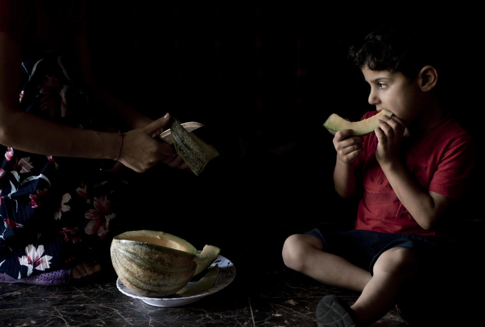 In this Aug. 22, 2018 photo, Ardawan, 4, eats melon on the kitchen floor of an orphanage for Yazidi children, in Sheikhan, Iraq. The child's father and four siblings have been missing since August 2014, when Islamic State militants took over northern and western Iraq; he lives at the orphanage with his mother and two remaining siblings. (AP Photo/Maya Alleruzzo)