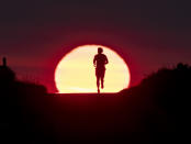 FILE - In this June 27, 2019 file photo a man runs on a small path as the sun rises in Frankfurt, Germany. The world could see average global temperatures 1.5 degrees Celsius (2.7 Fahrenheit) above the pre-industrial average for the first time in the coming five years, the U.N. weather agency said Thursday. The 1.5-C mark is a key threshold that countries have agreed to limit global warming to, if possible. Scientists say average temperatures around the world are already at least 1 C higher now than during the period from 1850-1900 because of man-made greenhouse emissions. (AP Photo/Michael Probst, file)