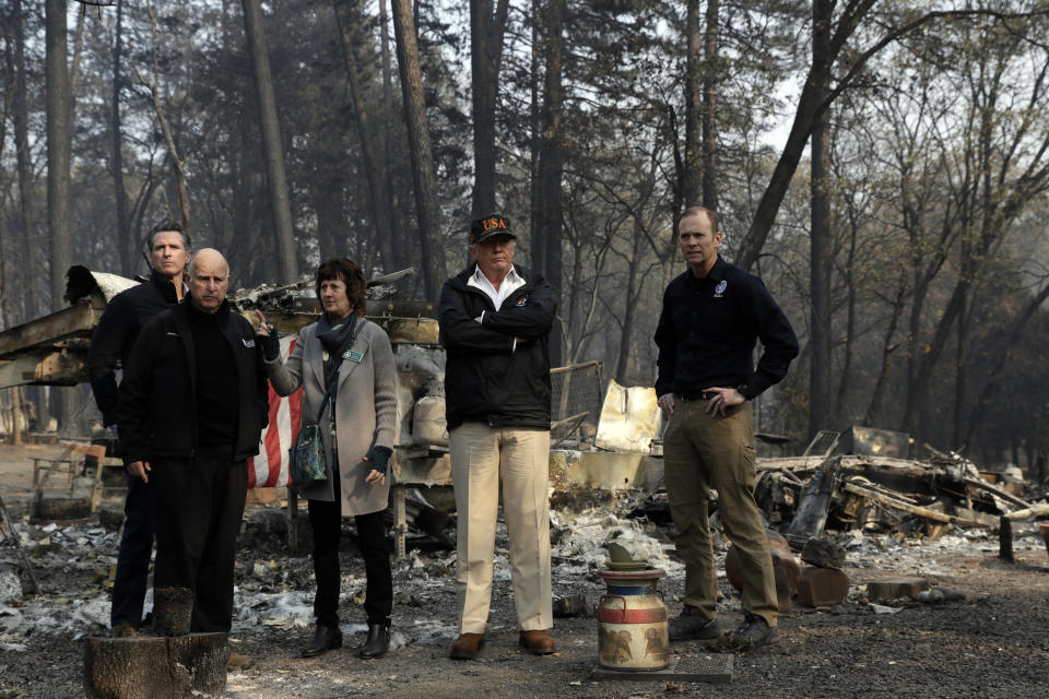 FILE - In this Nov. 17, 2018 file photo, President Donald Trump talks with from left, Gov.-elect Gavin Newsom, California Gov. Jerry Brown, Paradise Mayor Jody Jones and FEMA Administrator Brock Long during a visit to a neighborhood destroyed by the wildfires in Paradise, Calif. President Donald Trump is threatening to withhold Federal Emergency Management Agency money to help California cope with wildfires if the state doesn't improve its forest management practices. Trump tweeted Wednesday, Jan. 9, 2019, that California gets billions of dollars for fires that could have been prevented with better management. (AP Photo/Evan Vucci, File)
