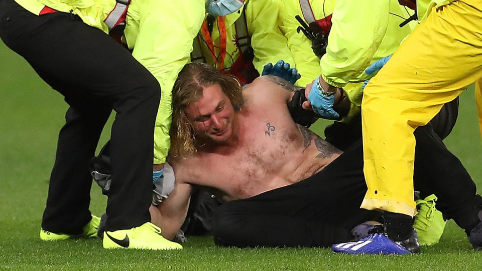 Pitch invader Jesse Hayer is pictured being tackled to the ground by security at Optus Stadium.