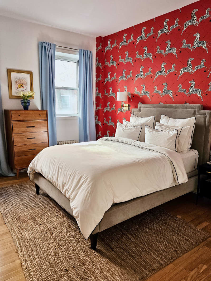 white bedroom with red zebra wallpaper accent wall and light blue curtains