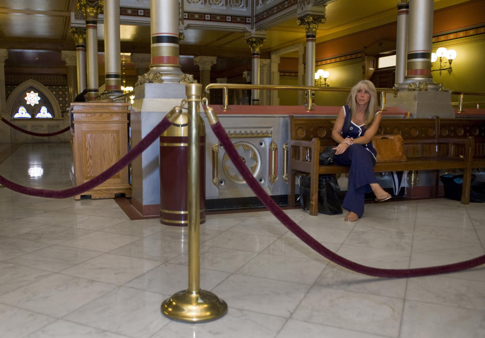 Tracey Scalzi, owner of two roll-your-own cigarette shops, sits behind a stanchions outside the Hall of the House of Representatives during a special session at the Capitol in Hartford, Conn., Tuesday, June 12, 2012. Connecticut lawmakers have returned to the state Capitol to finish work on two wide-ranging budget-related bills. Tucked into one of the budget bills is a proposal to tax roll-your-own tobacco shops. Scalzi says the tax will likely force her store to close and lay off employees. (AP Photo/Jessica Hill)