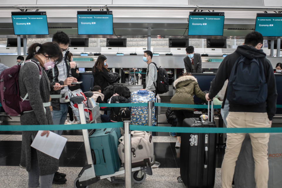 Passengers wearing protective masks stand in line near Cathay Pacific Airways Ltd. check in counters at the Hong Kong International Airport in Hong Kong.