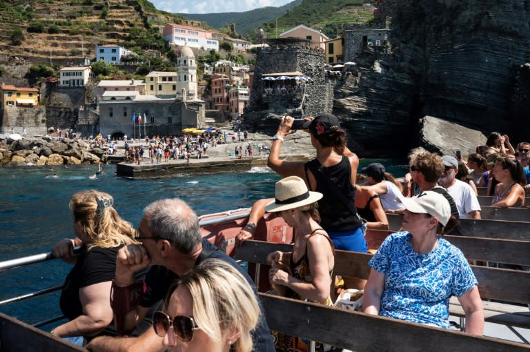 Tour boat passengers gawk at the town of Vernazza, one of the picturesque Cinque Terre villages along the Italian Riviera that are thronged by tourists during the high season (MARCO BERTORELLO)