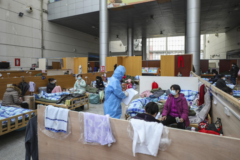 In this Friday, Feb. 21, 2020, photo, a doctor in a protective suit checks with patients at a temporary hospital at Tazihu Gymnasium in Wuhan in central China's Hubei province. China's leadership sounded a cautious note Friday about the country's progress in halting the spread of the new virus that has now killed more than 2,200 people, after several days of upbeat messages. (Chinatopix via AP)