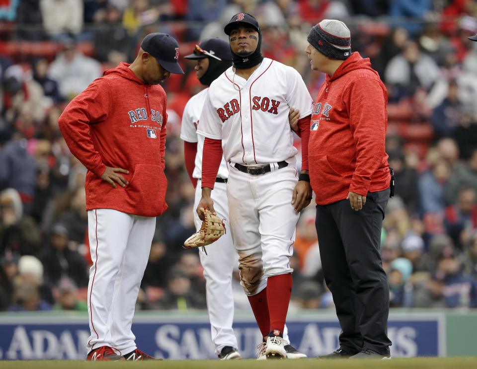 Xander Bogaerts, center, is assisted as he leaves the field as manager Alex Cora, left, looks on in the seventh inning of a baseball game against the Tampa Bay Rays on Sunday. (AP)