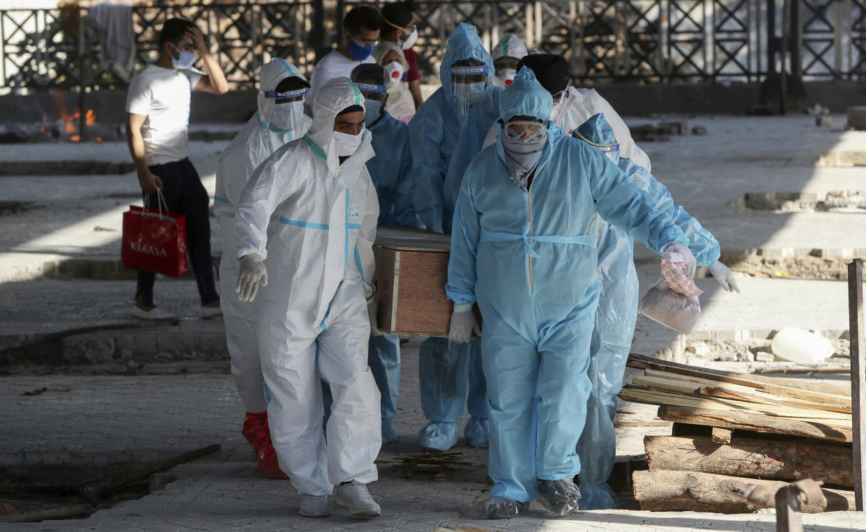 FILE - In this April 26, 2021, file photo, health workers and relatives carry the body of a COVID-19 victim for cremation in Jammu, India. India crossed a grim milestone Wednesday, April 28, 2021 of 200,000 people lost to the coronavirus as a devastating surge of new infections tears through dense cities and rural areas alike and overwhelms health care systems on the brink of collapse. (AP Photo/Channi Anand, File)