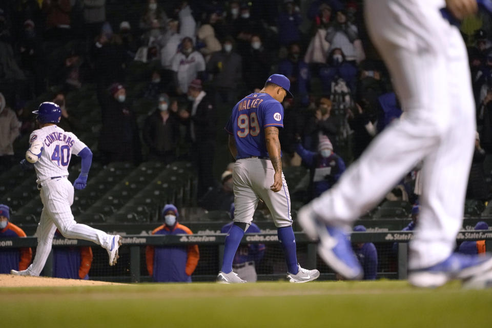 New York Mets starting pitcher Taijuan Walker (99) walks off the mound with his head down after walking Chicago Cubs' Willson Contreras (40) with the bases loaded, scoring Eric Sogard and advancing Jake Arrieta, foreground, to third during the fourth inning of a baseball game Tuesday, April 20, 2021, in Chicago. (AP Photo/Charles Rex Arbogast)