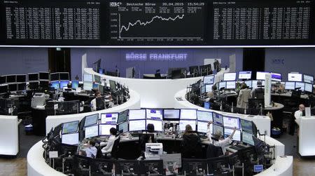 Traders are pictured at their desks in front of the DAX board at the Frankfurt stock exchange April 20, 2015. REUTERS/Remote/Staff