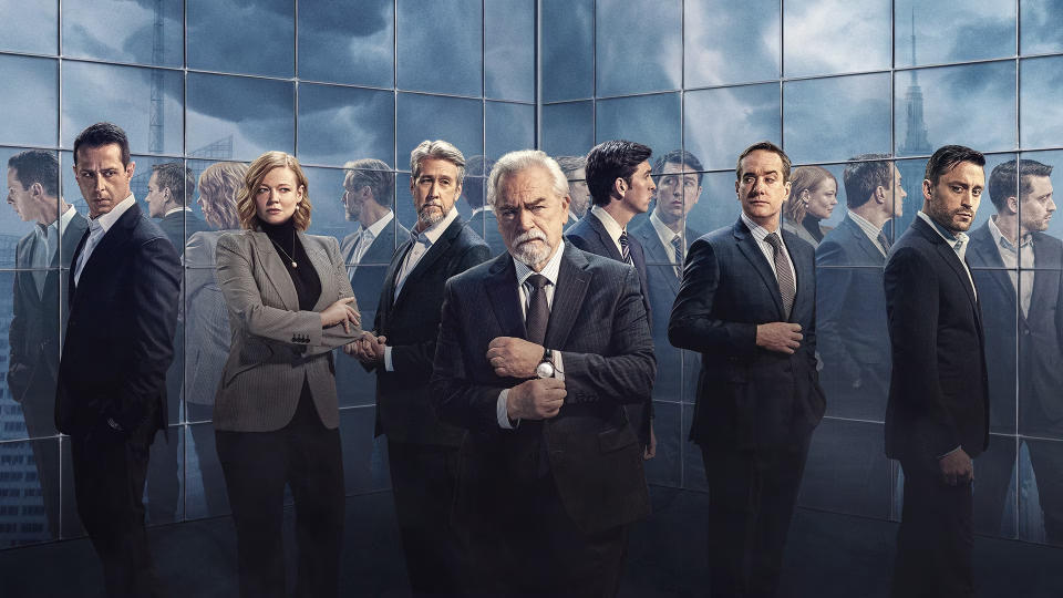 Succession season 4 key art featuring (L to R) Jeremy Strong as Kendall, Sarah Snook as Shiv, Alan Ruck as Connor, Brian Cox as Logan, Nicholas Braun as Greg, Matthew Macfadyen as Tom and Kieran Culkin as Roman in front of a skyscraper