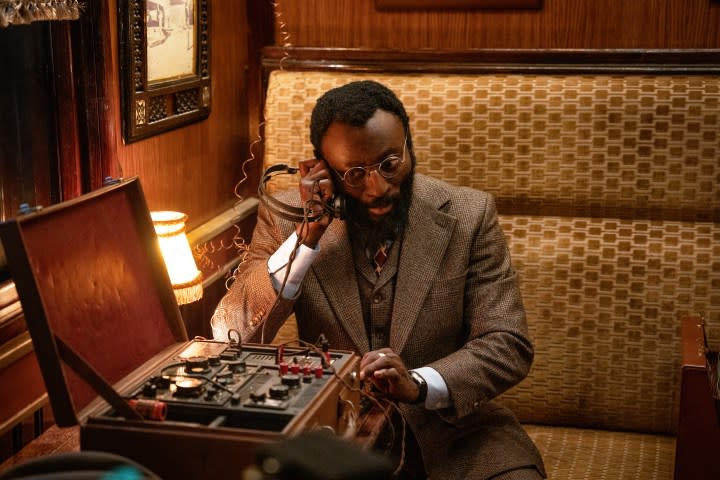 A man sits in a booth and listens to a headphone.