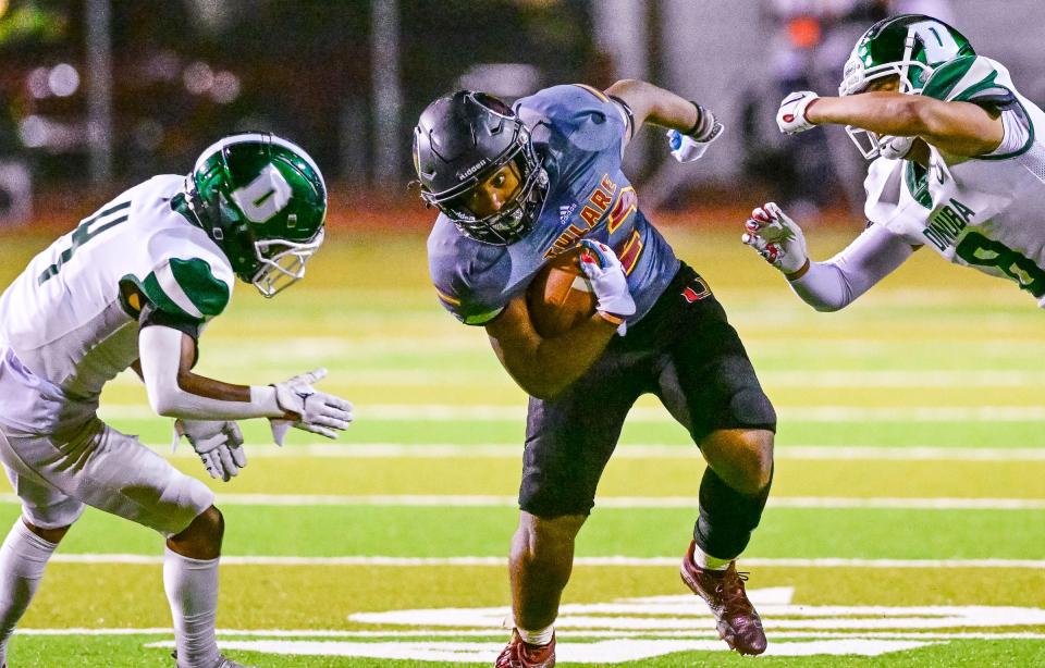 Tulare Union's Tieler Peterson, center, evades Dinuba's Andrew Ambriz, left, and Herbert Denny in a West Yosemite League high school football game Thursday, October 20, 2022. 