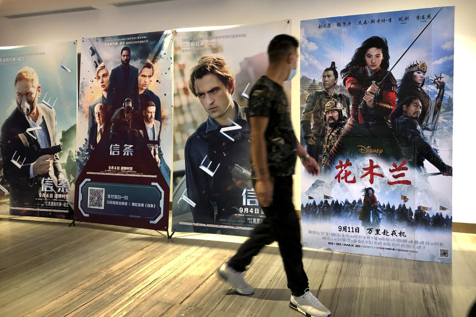 Un hombre con mascarilla pasa junto a un póster de la película de Disney "Mulan" en un cine en Beijing, el 11 de septiembre del 2020. (AP Foto/Mark Schiefelbein)