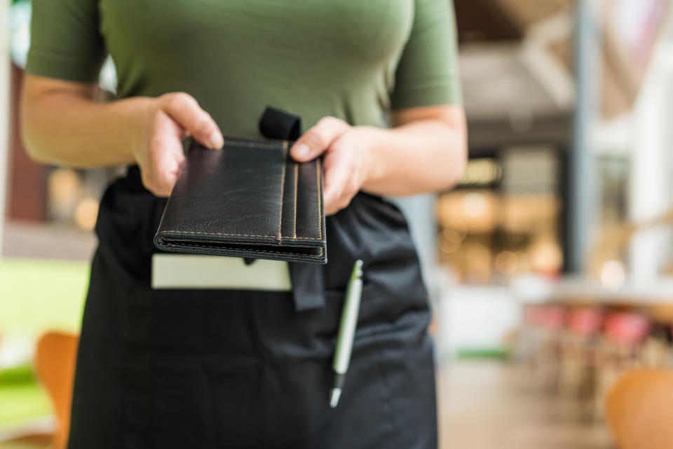 Close-up of a server holding a black check presenter at a restaurant